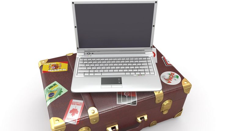 Auf einem Koffer mit Aufklebern steht ein Laptop