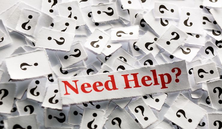 Viele Papierschnipsel mit Fragezeichen und dazwischen auf einem Zettel in roter Schrift: "Need Help?".