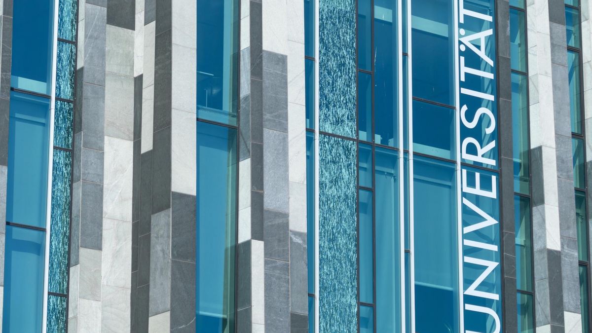 zur Vergrößerungsansicht des Bildes: Glasfassade des Augusteums der Universität Leipzig, vertikal ist der Schriftzug „Universität” zu erkennen.