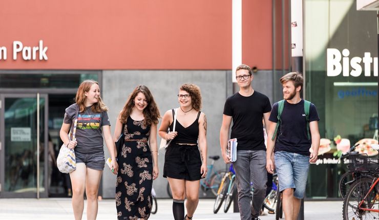 fünf lachende Studierende laufen über den Campus Augustusplatz