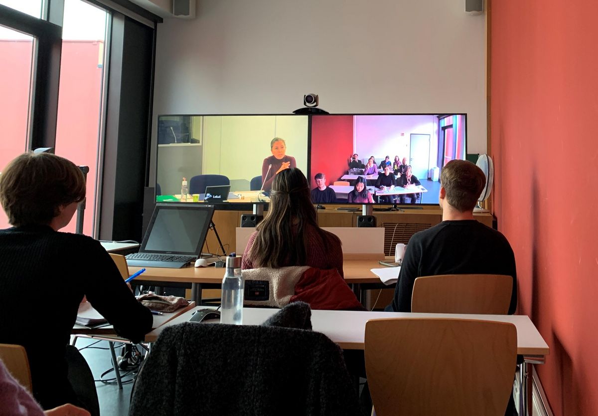 zur Vergrößerungsansicht des Bildes: Videokonferenz nach Brüssel. Die Studierenden verfolgen aufmerksam das Geschehen auf den Monitoren.