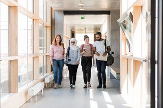 Vier Studierende laufen nebeneinander durch einen Gang im GWZ.