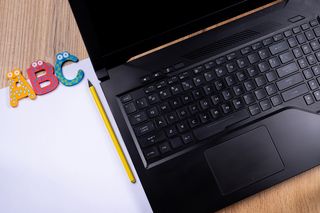 Laptop mit Block, Stift und Buchstaben