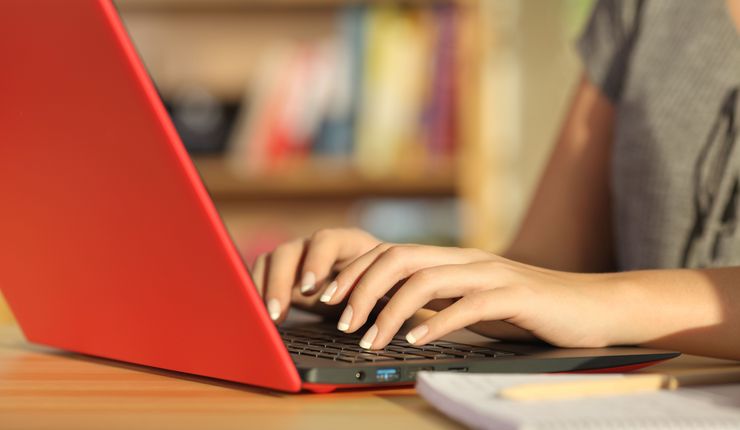 Eine Frau schreibt auf einem roten Laptop.