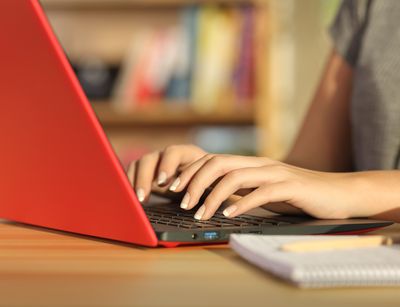 Eine Frau schreibt auf einem roten Laptop.
