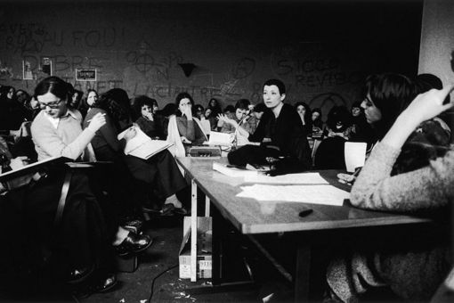 Es handelt sich um ein Schwarz-Weiß-Foto aus den 1970er Jahren. Es wird eine Seminarsituation von ausschließlich weiblichen Studierenden dargestellt. Etwa in der Mitte sitzt eine etwas ältere Frau, die ernst in die Runde schaut, aber viele der anwesenden Studierenden schauen weg oder ziemlich gelangweilt.