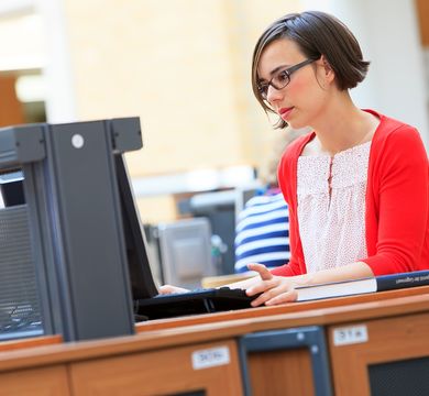 Foto: Eine Junge Frau sitzt in der Universitätsbibliothek am Laptop