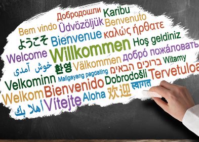 Das Wort Willkommen wird in verschiedenen Sprachen und verschiedenen Farben an eine Tafel geschrieben. Foto: Colourbox