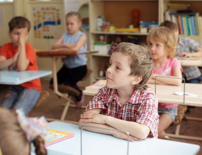 Schüler einer Grundschulklasse sitzen im Klassenraum an ihren Tischen.