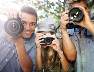 Drei junge Leute fotografieren mit Fotoapparat.