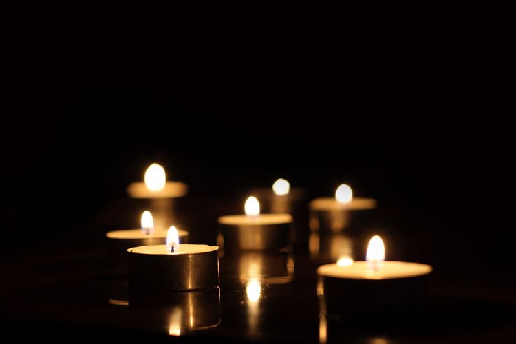 Das Bild zeigt erleuchtete Kerzen in einem dunklen Raum.