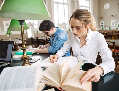 Ein Student und eine Studentin arbeiten konzentriert in der Bibliothek.