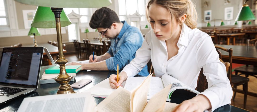 Ein Student und eine Studentin arbeiten konzentriert in der Bibliothek.