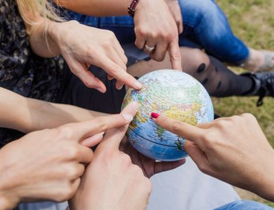 Colour photo: various hands point to a small globe