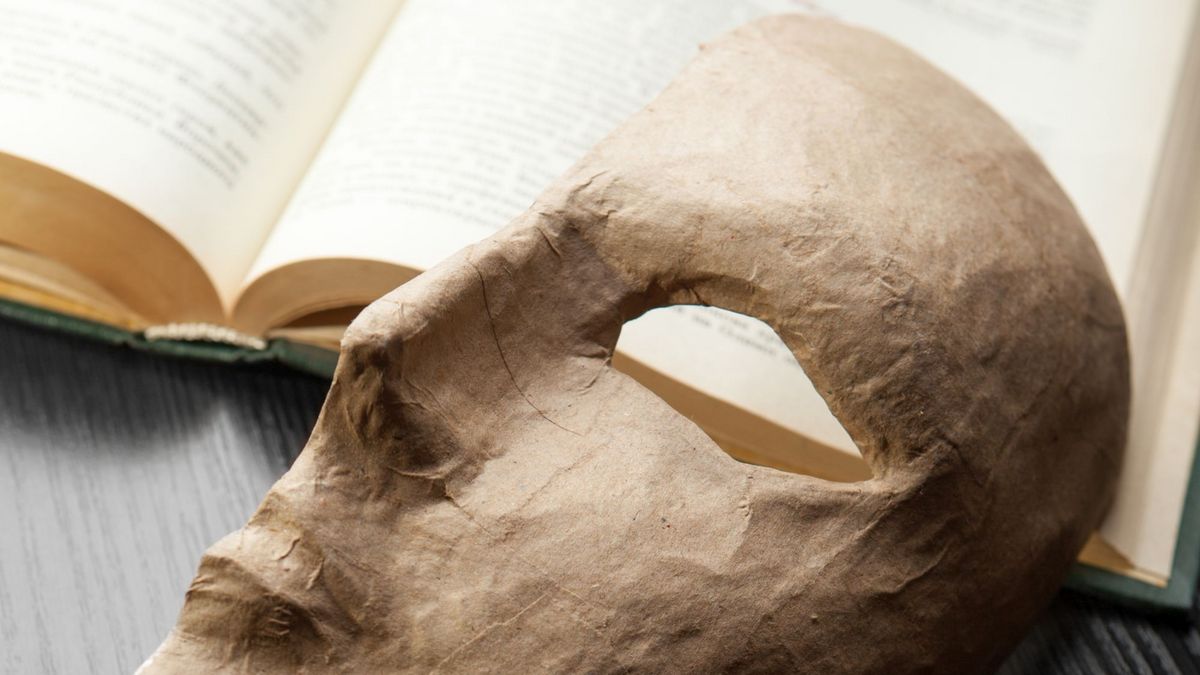 enlarge the image: Photo of a theatre mask which is placed on an open book