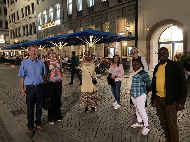 Sieben Personen stehen des Nachts im Zentrum der Stadt Leipzig vor einigen Restaurants.