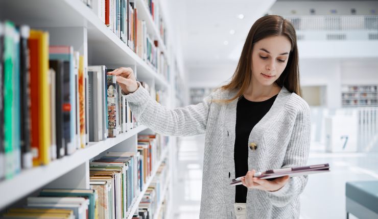 Eine Studentin sucht in der Bibliothek nach Literatur.