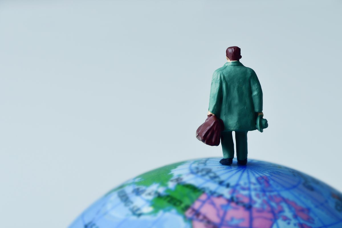 Eine kleine Figur eines Menschen steht mit dem Rücken zur Kamera auf einem Globus