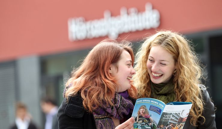 Zwei junge Frauen informieren sich beim Studieninformationstag über Studienmöglichkeiten an der Universität Leipzig.