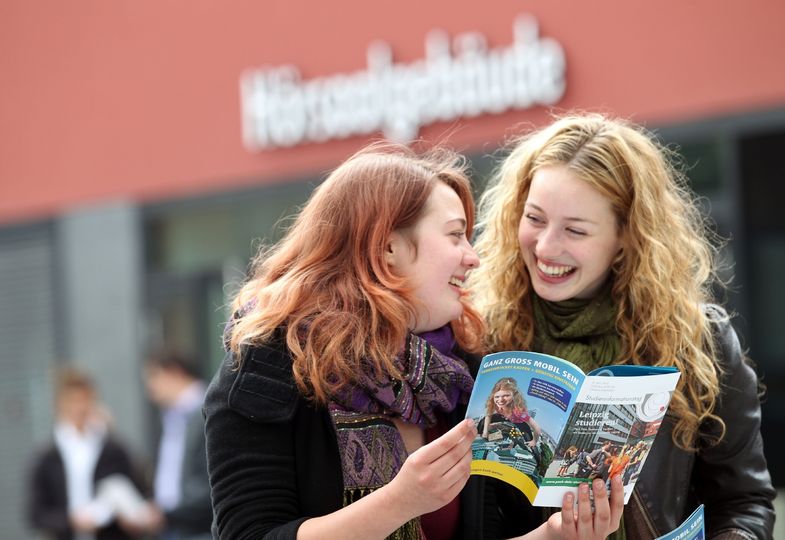 Zwei junge Frauen informieren sich beim Studieninformationstag über Studienmöglichkeiten an der Universität Leipzig.