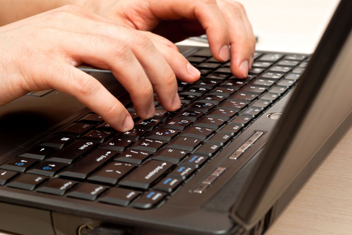 zur Vergrößerungsansicht des Bildes: Auf dem Foto sind zwei männliche Hände zu sehen, die auf einer Laptoptastatur etwas eintippen.